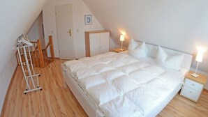 Un dormitori amb un llit gran, una vetustat, una làmpada, un armari i una escala de fusta.