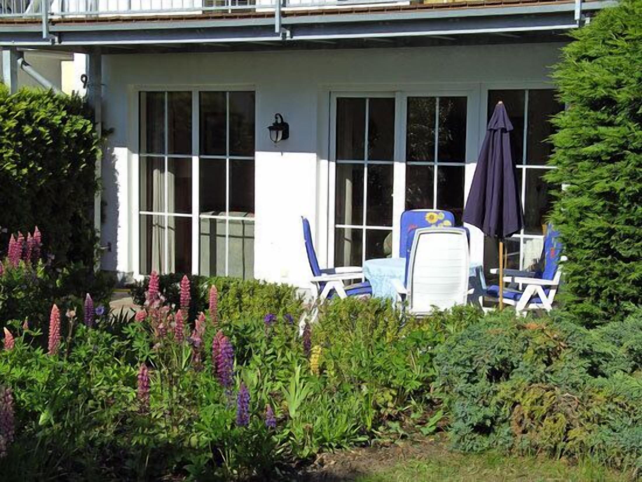 A house with a covered porch, two chairs, and a table.
