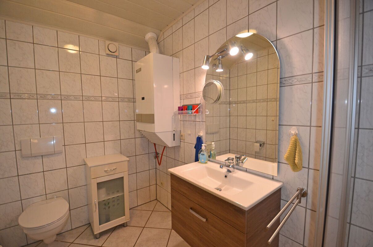 Un baño con inodoro, armario, lavabo y espejo.