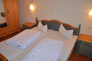 Ein Doppelbett mit zwei Kissen, einem Holz-Kopfteil und zwei Nachttischen mit Lampen.