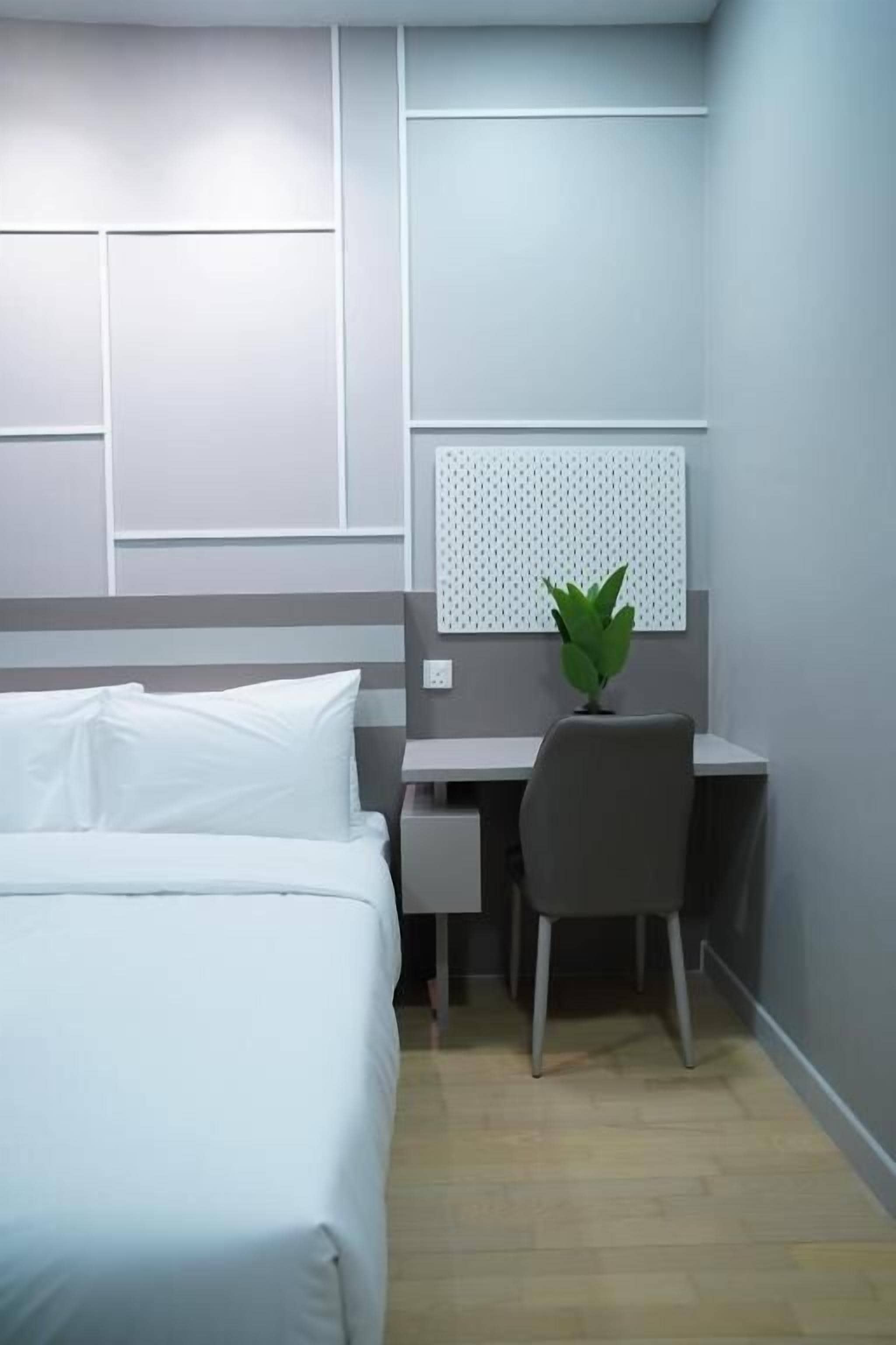Una habitación de hotel con cama, escritorio, silla y una planta en maceta.