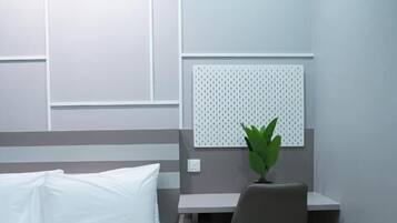 Una habitación de hotel con cama, escritorio, silla y una planta en maceta.
