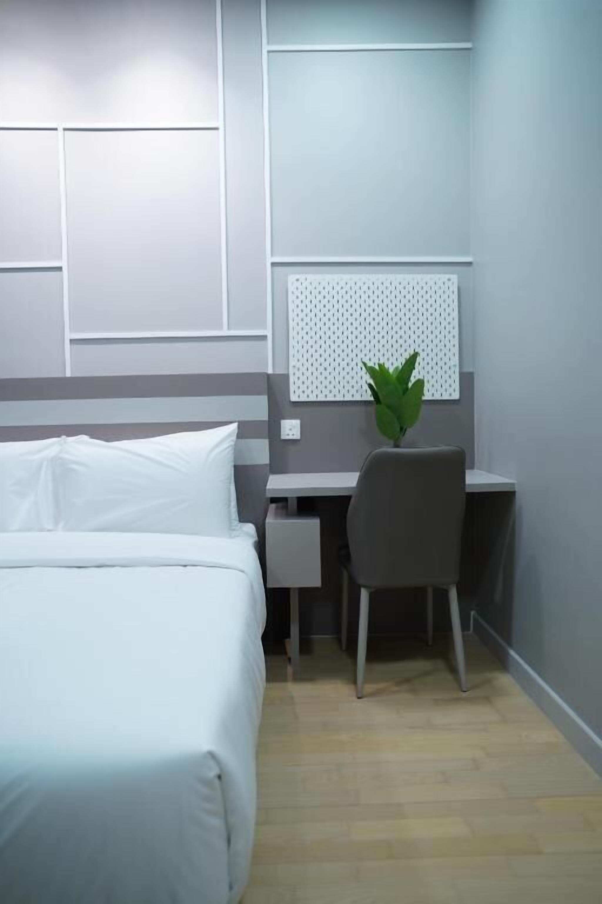 A hotel room with a bed, a desk, and a chair.
