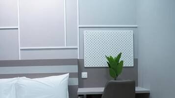 A hotel room with a bed, a desk, and a chair.
