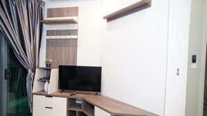 Un saló modern amb un moble televisió integrat, un televisor de pantalla plana i una porta de vidre que dona a un balcó.