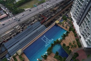 A high-rise building with a rooftop swimming pool and a view of a busy highway. - Datum Jelatek Residence  (Wilayah Persekutuan)