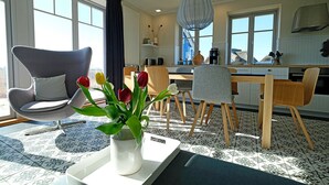 Una cocina moderna con comedor, que presenta una silla original, un jarrón con tulipanes e iluminación colgante.