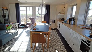 Un espacio habitable moderno con comedor, cocina y ventanas grandes que ofrecen vistas.
