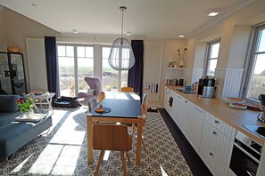 A modern living space with a dining area, kitchen, and large windows offering a view. - Close to the beach and with a lake view, spread over 2 floors, with a washing machine, sauna, and internet (Dranske)