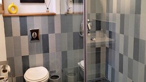 Een moderne badkamer met een douchecabine van glas, een toilet en een wastafel.