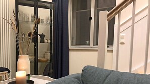 Ein Wohnzimmer mit einer Couch, einem Tisch mit Kerze und einer Vitrine mit Dekoration.