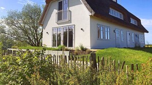 Ein zweistöckiges Haus mit geneigtem Dach, großen Fenstern und einem sichtbaren Balkon.