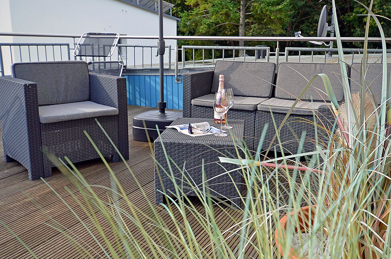 Outdoor wicker furniture with cushions, a bottle of wine, and a menu on a table.