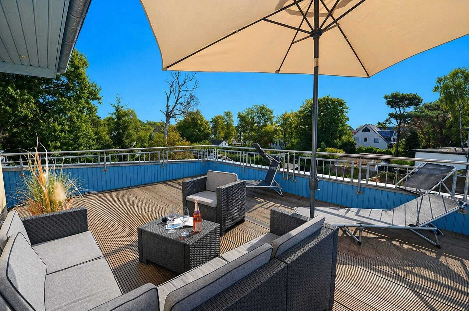 An outdoor deck with a pool, lounge chairs, and a table with drinks.