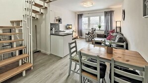 A modern kitchen with a central island, a dining area with a wooden table and chairs, and a staircase with a unique design. - Vacation rental with a view of the water, sleeps up to 5 people with 2 bedrooms, just 60 meters from the water (Dranske)
