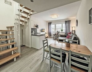 A modern kitchen with a central island, a dining area with a wooden table and chairs, and a staircase with a unique design. - Vacation rental with a view of the water, sleeps up to 5 people with 2 bedrooms, just 60 meters from the water (Dranske)