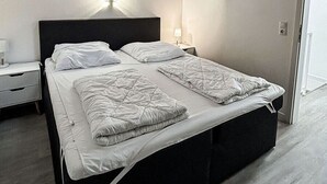 A bedroom with a bed, bedside tables, and a nightstand. - Vacation rental with a view of the water, sleeps up to 5 people with 2 bedrooms, just 60 meters from the water (Dranske)