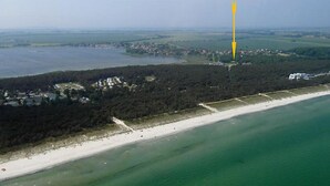 Eine Luftaufnahme einer Küstenregion mit Strand, bewaldetem Gebiet und einem Gewässer.
