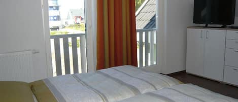 Un dormitorio con cama, televisor y vistas al exterior.