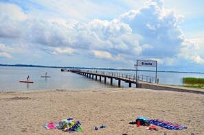 A beach with a pier extending into the water, a sign reading 'Dranske,' and a sandy area with beach equipment. - Apartment complex in a quiet location, just 80 meters from the water, 2 bedrooms (Dranske)