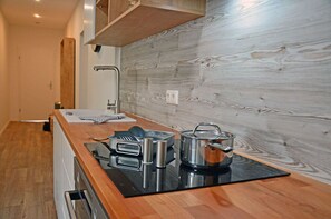 A modern kitchen with a wooden countertop, built-in oven, and a backsplash with a wood grain pattern. - Apartment complex in a quiet location, just 80 meters from the water, 2 bedrooms (Dranske)