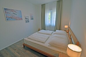 Ein Schlafzimmer mit einem großen Bett, einer Nachttischlampe und einem Fenster mit Vorhängen.
