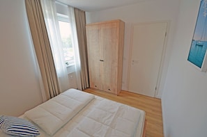 A bedroom with a bed, a wardrobe, and a door. - Apartment complex in a quiet location, just 80 meters from the water; accommodates up to 2 people (Dranske)
