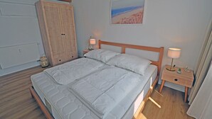 Ein Schlafzimmer mit einem Bett, Nachttischen, einem Kleiderschrank und einem Bild an der Wand.