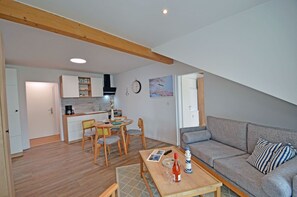 Een functionele leefruimte met eethoek, kitchenette en een zithoek.