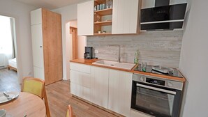 Eine kompakte Küche mit weißen Schränken, einer Holz Arbeitsplatte, einem eingebauten Ofen und einer Kaffeemaschine.