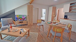 Ein modernes Wohnzimmer mit Fernseher, Sofa und Essbereich.