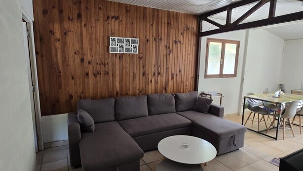 Ein Wohnzimmer mit einer Couch, einem runden Couchtisch und einer Holzwand mit einem gerahmten Foto.
