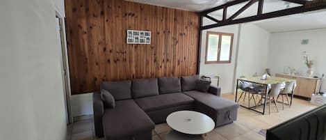 A living room with a sofa, a round coffee table, and a wooden wall with a framed photo.