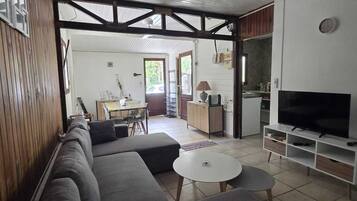 Ein Wohnzimmer mit Sofa, Fernseher und Essbereich mit Tisch und Stühlen.