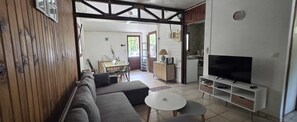 Un salon comprenant un canapé, un téléviseur et un coin repas avec une table et des chaises.