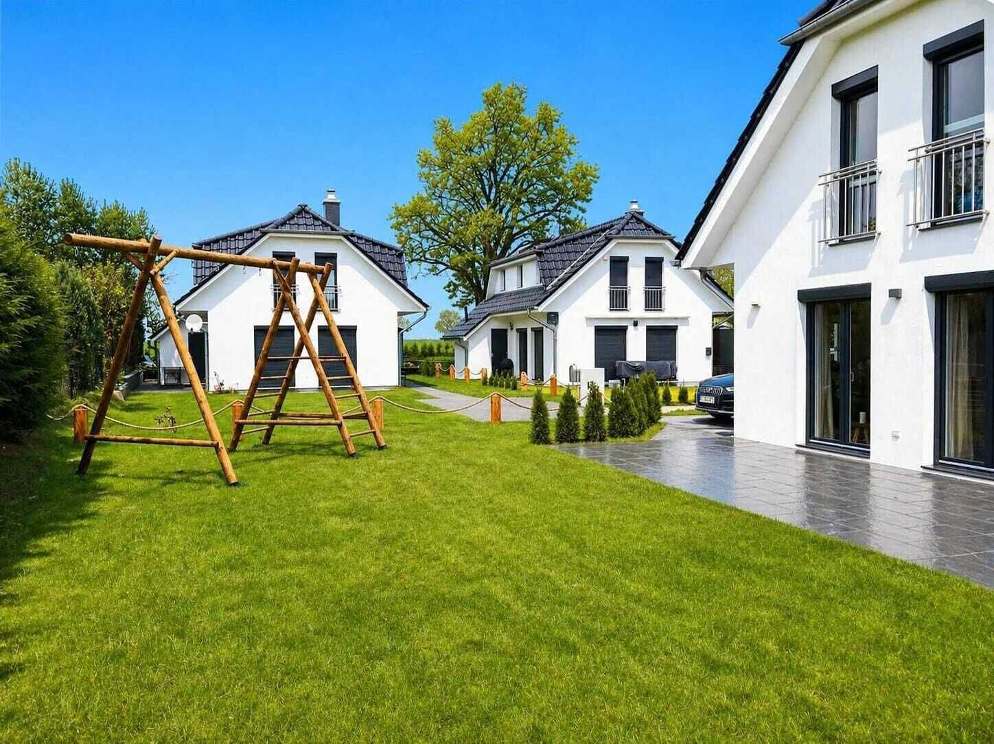 A residential area with modern houses, a wooden swing set, and a well-maintained lawn.