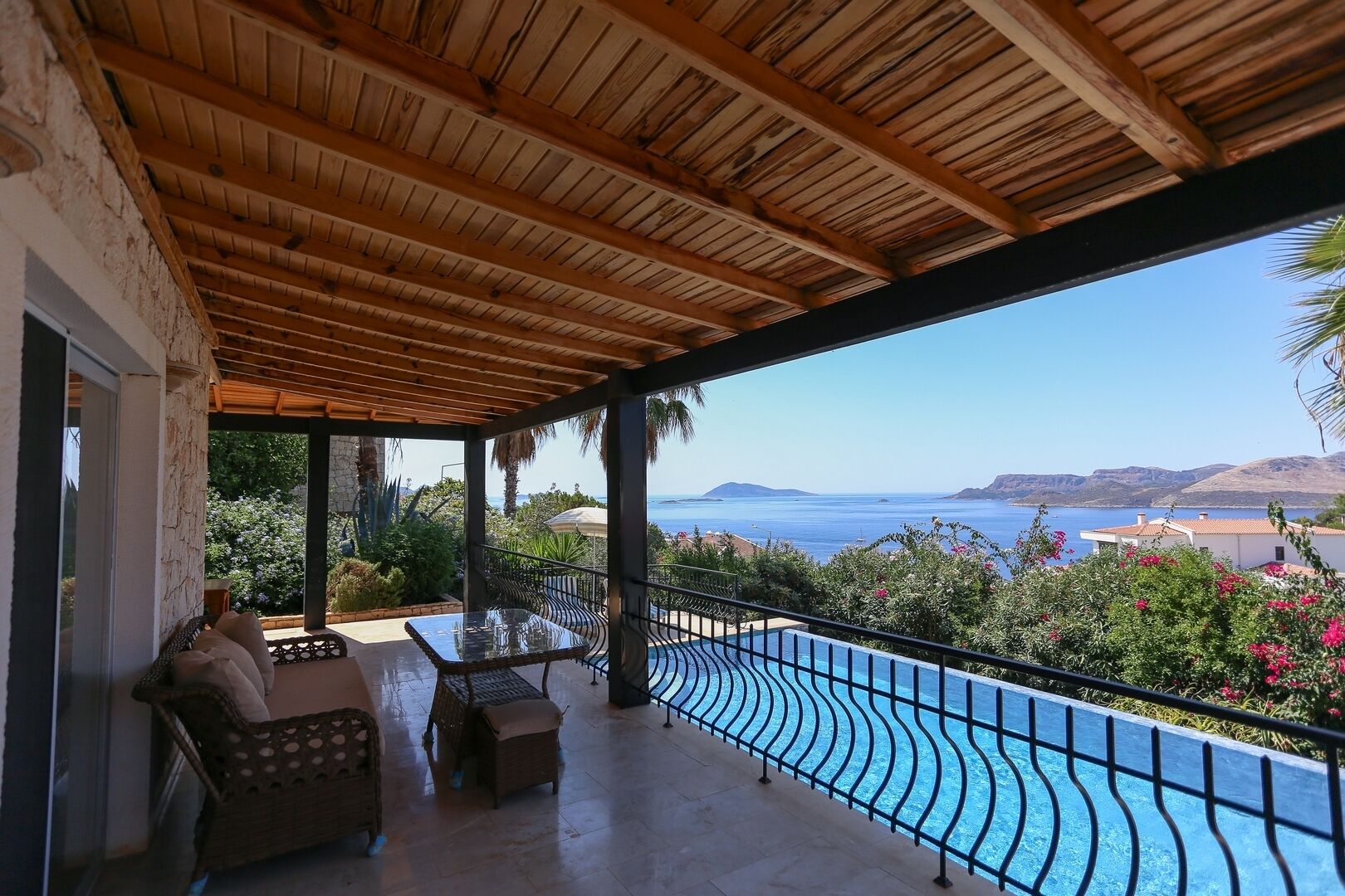 A covered outdoor area with a pool, seating, and a view of the sea.