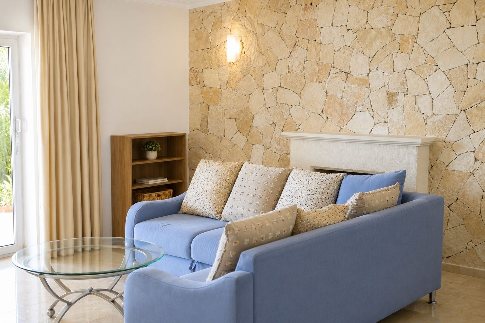 Ein Wohnzimmer mit einem blauen Sofa, einem Glastisch, einer Steinwand und einem Kamin.
