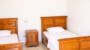 A room with two wooden beds, a small wooden nightstand, and a white wall. - Villa Tavla (KAŞ)