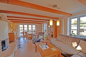 A spacious living area with a wooden ceiling, a fireplace, a sofa, a coffee table, and a dining area with chairs and a table. - Spanning 2 floors on the Bodden, with a terrace featuring patio furniture, a washing machine, and internet access (Polchow)