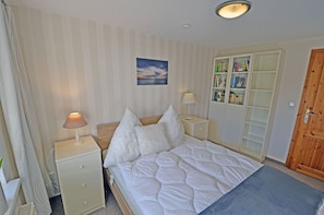 A bedroom with a bed, bedside tables, a nightstand, a lamp, a bookshelf, and a door. - Spanning 2 floors on the Bodden, with a terrace featuring patio furniture, a washing machine, and internet access (Polchow)