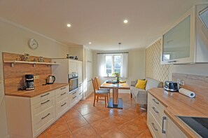 A modern kitchen with white cabinets, a coffee machine, and a dining area with a table and chairs.