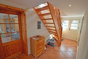 A wooden staircase leading to an upper floor, a wooden dresser with drawers, a window with a view, and a door with frosted glass panels. - Spanning 2 floors on the Bodden, with a terrace featuring patio furniture, a washing machine, and internet access (Polchow)