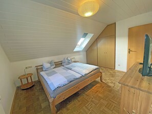 A bedroom with a sloped ceiling, a skylight, a bed with pillows, a bedside table, and a wardrobe. - Quiet, central location, about 400 meters from the Baltic Sea beach, 3 bedrooms, sleeps up to 8 people (Glowe)