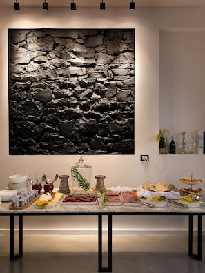 A buffet setup with a stone wall backdrop, various food items, and a wine bottle.