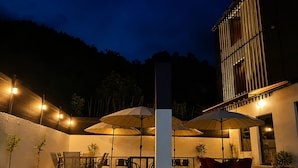 An outdoor patio area with tables and chairs, umbrellas, and potted plants. - The Green O (Oni)