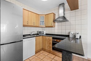 A modern kitchen with stainless steel appliances, wooden cabinets, and a black granite countertop. - Vacation Home 'Casa Canas' with Sea View, Wi-Fi and Air Conditioning (Playa Blanca)