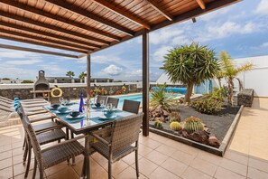 An outdoor patio with a dining table set for four, surrounded by wicker chairs. - Vacation Home 'Casa Canas' with Sea View, Wi-Fi and Air Conditioning (Playa Blanca)