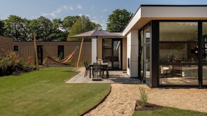 Een modern huis met een terras, een hangmat en een eethoek.