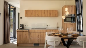 Een moderne keuken met houten kastjes, een inbouwoven en een eethoek met een tafel voor vier personen.